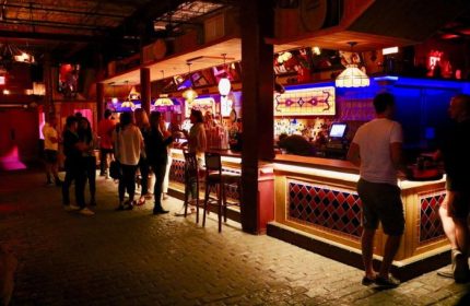 Gay bar in New York: 3 Dollar Bill interior. People at the bar, warm lighting, brick floor. Gay travel advice, nightlife, social scene.