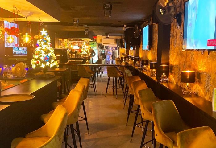 Interior of 3 Monkeys gay bar in Torremolinos, Spain. Christmas tree, bar stools, and TVs create a welcoming atmosphere. Gay travel advice.