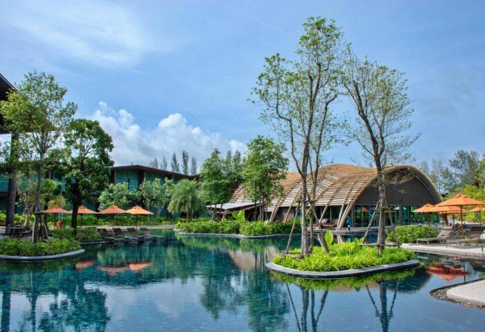 Kalima Resort & Villas Khao Lak pool view. Tropical gay travel destination with modern architecture, lush greenery, and serene water features.
