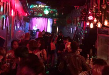 Inside Thi Bar: A lively gay bar scene with a DJ, dance floor, and patrons enjoying the vibrant atmosphere. Gay travel advice.