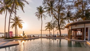 SAii Laguna Phuket pool view at sunset. Palm trees, beach chairs, and a bar create a relaxing atmosphere. Gay men travel advice. 361488022.jpg
