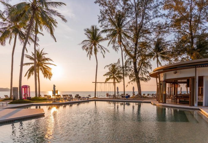 SAii Laguna Phuket pool view at sunset. Palm trees, beach chairs, and a bar create a relaxing atmosphere. Gay men travel advice. 361488022.jpg