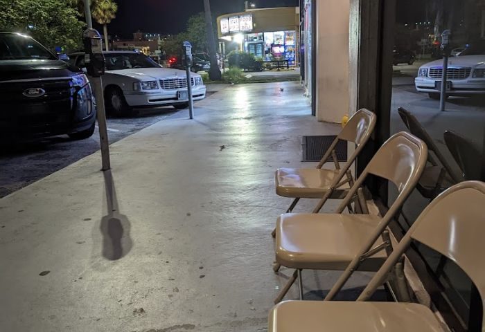 The Clubhouse II: Night scene with chairs outside a gay bar. Cars parked on street. Travel advice for gay men. 4-14.jpg.