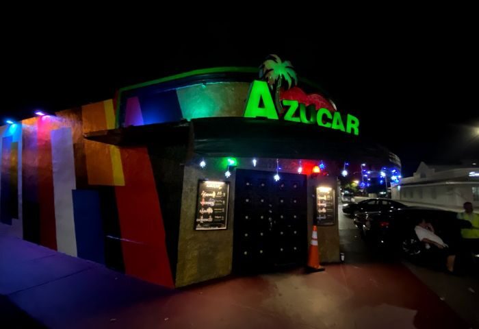 Azucar Nightclub's exterior at night. The gay bar features rainbow colors and a bright green sign. A popular spot for gay men's travel.