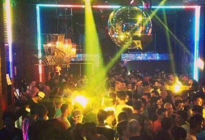 Gay men's travel advice: A crowded gay club, possibly SCORE, with a disco ball, stage lights, and a large group of people dancing.
