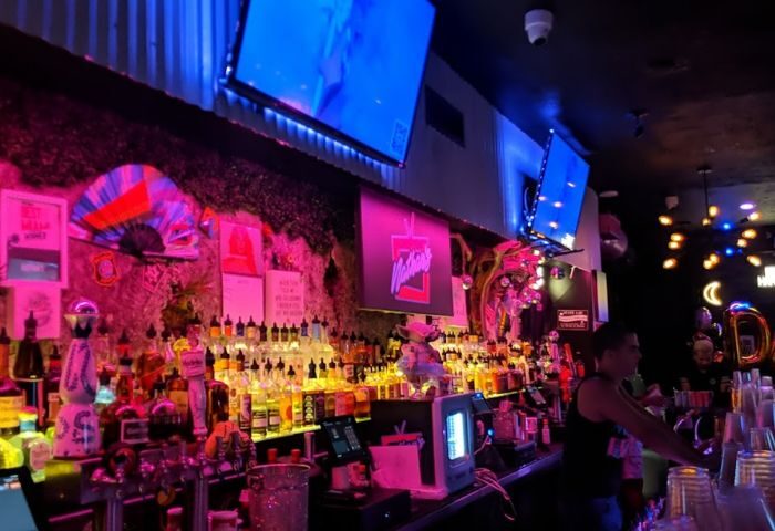 Nathan's Beach Club bar interior at night. Colorful bottles line the shelves, with screens above. Gay travel destination. 4-25.jpg