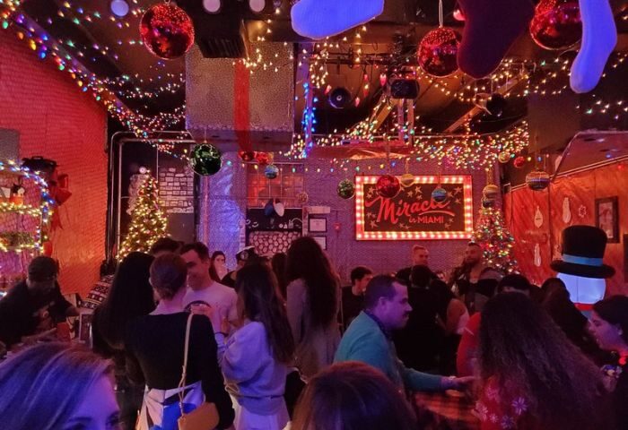 Gramps gay bar: Christmas lights, ornaments, and a Miracle in Miami sign adorn the bar. People mingle at this gay travel destination.