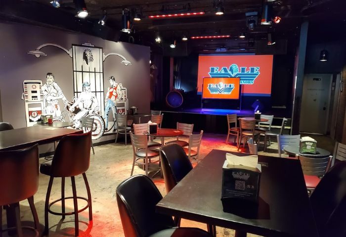 Interior of The Eagle Wilton Manors, a gay bar. Tables, chairs, stage with logo. Gay travel destination. 4-9.jpg.