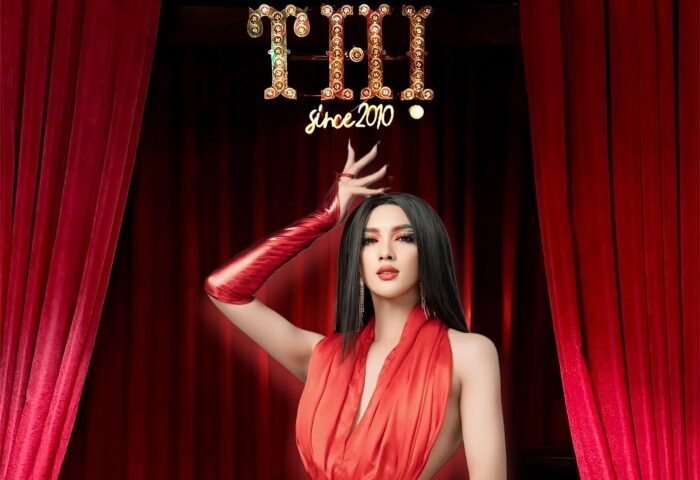 Thi Bar: Drag queen in red dress and gloves poses in front of red curtains. Gay travel nightlife advice.