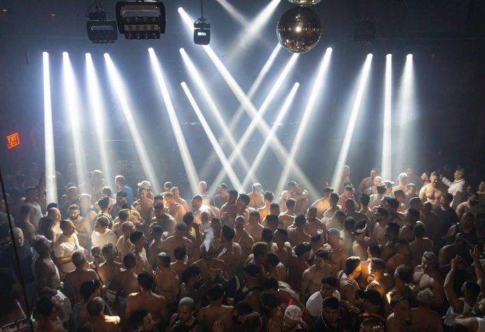 Gay Industry party: A large, shirtless crowd of men dancing under bright lights and a disco ball. Gay travel advice, nightlife.
