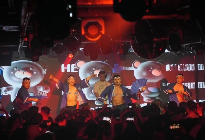 Gay travel destination: Go-go dancers entertain a crowd at a gay club. Nightlife scene with shirtless men. Party atmosphere.
