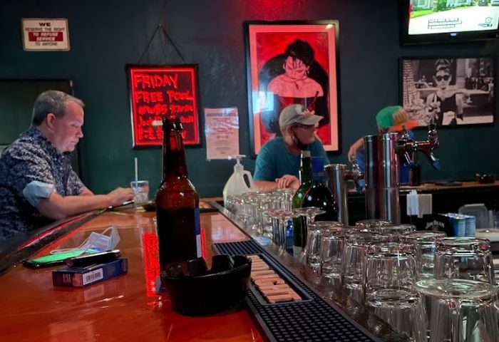 The Corner Pub interior. Patrons at the bar, beer, glasses, and art. Gay men's travel advice. 5-1.jpg.