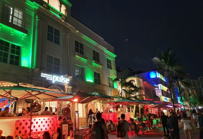 Night view of Palace Bar, a gay bar in Miami Beach. The building is lit with green lights. People are dining outside. 5-20.jpg