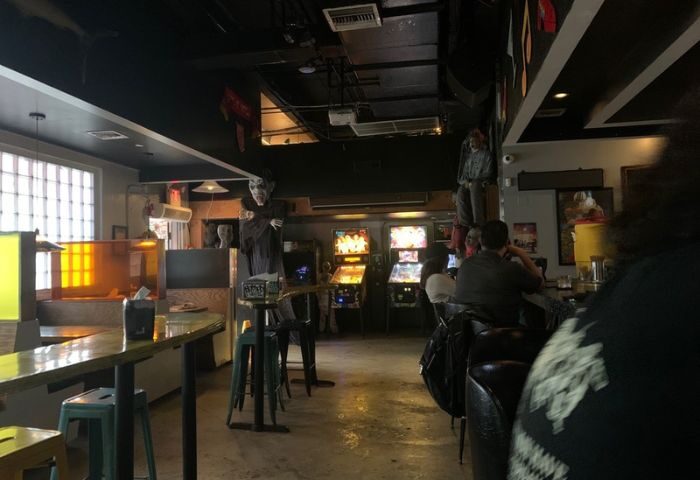 Gramps gay bar interior. Pinball machines, bar seating, and spooky decor create a unique atmosphere for gay men's travel experiences.
