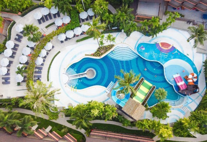 Aerial view of Courtyard Phuket, Patong Beach Resort pool area. Palm trees, lounge chairs, and water slides. Gay travel advice. 526577744.jpg