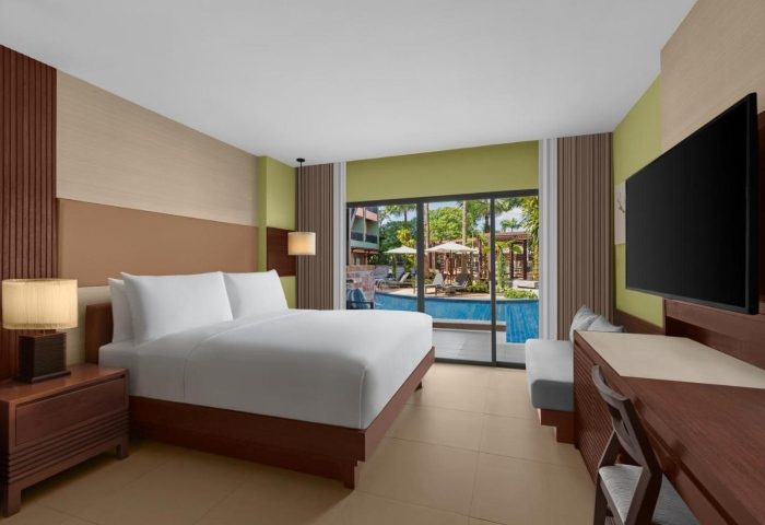 Courtyard Phuket, Patong Beach Resort room with a king bed, desk, and a view of the pool. Perfect for gay men's travel to Phuket.