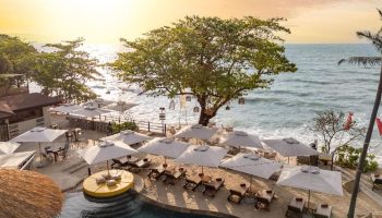 SAii Koh Samui Villas view. Beachfront resort with pool, umbrellas, and lounge chairs overlooking the ocean. Tropical gay travel destination.
