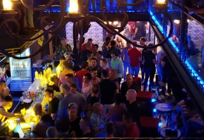Gay party at a strip bar in Puerto Vallarta, Mexico. Men are drinking and socializing in a crowded, dimly lit space.