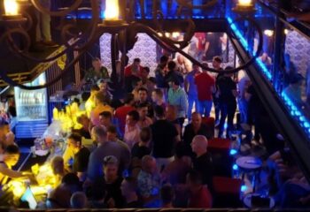 Gay party at a strip bar in Puerto Vallarta, Mexico. Men are drinking and socializing in a crowded, dimly lit space.