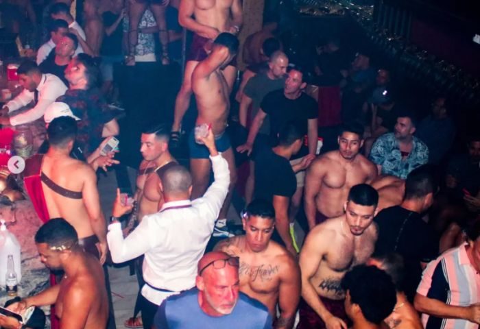 Gay party in Puerto Vallarta strip bar. Shirtless men, drinks, and a lively atmosphere. Gay travel nightlife.