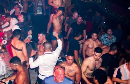 Gay party in Puerto Vallarta strip bar. Shirtless men, drinks, and a lively atmosphere. Gay travel nightlife.
