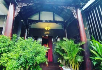 Entrance to 69 Sauna, Ho Chi Minh. Ornate wood frame, red curtain, plants. Gay travel advice, Vietnam nightlife.