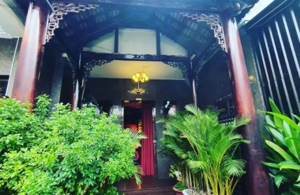 Entrance to 69 Sauna, Ho Chi Minh. Ornate wood frame, red curtain, plants. Gay travel advice, Vietnam nightlife.