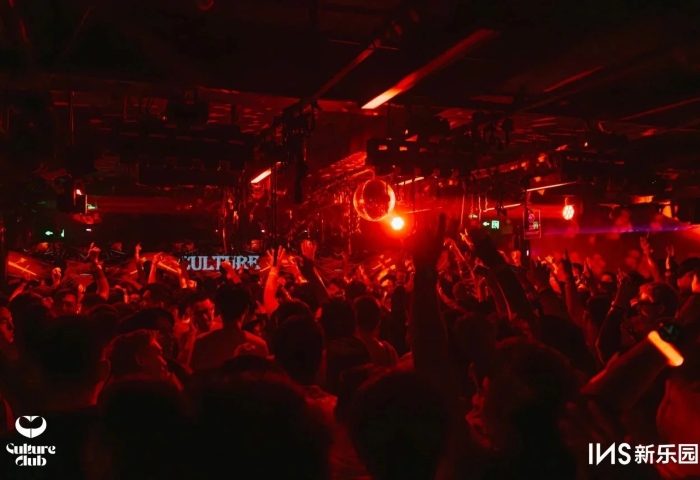 Gay travel: Red-lit dance floor at Culture Club. Crowd with hands up, disco ball. Nightlife scene, gay clubbing, party atmosphere.