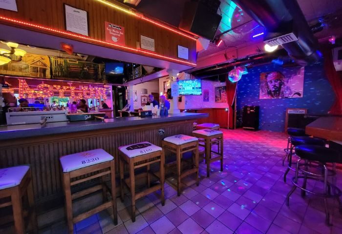 Gay bar Asylum in Key West. Stools line the bar, disco ball, and colorful lights create a party atmosphere. Travel advice for gay men.