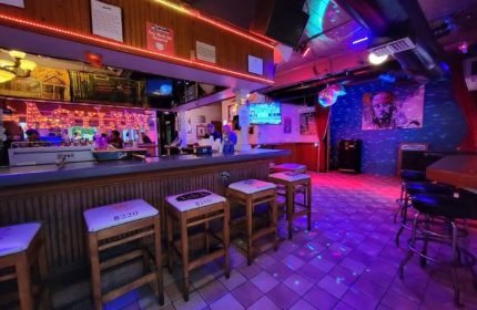 Gay bar Asylum in Key West. Stools line the bar, disco ball, and colorful lights create a party atmosphere. Travel advice for gay men.