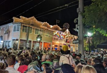 Gay party at 801 Bourbon Bar in Key West. Crowd gathers for drinks, festive lights, and rainbow flags. Gay travel destination.