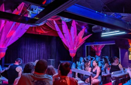 Gay party at 801 Bourbon Bar in Key West. People enjoy drinks at a show in a vibrant, colorful gay bar. Gay travel advice.