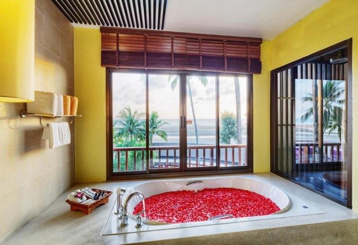 Apsara Beachfront Resort bathroom with tub filled with red petals, ocean view. Gay travel luxury villa 96955546.jpg.
