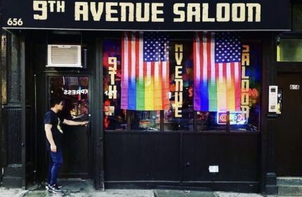 9th Avenue Saloon, a gay bar in New York. Rainbow flags hang in the window. A man enters the bar. Gay travel destination.