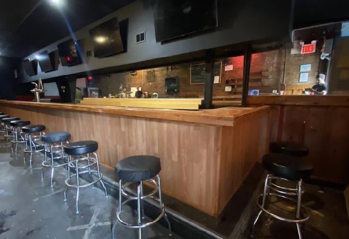Interior of 9th Avenue Saloon, a gay bar in New York. Bar stools line the counter. TVs are mounted above the bar. Gay travel advice.
