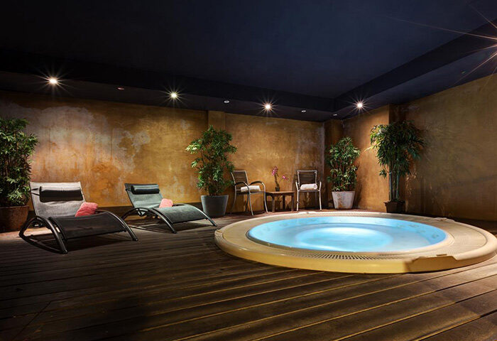 Acevi Villarroel Hotel spa area in Barcelona's Gaixample. Hot tub, lounge chairs, and plants create a relaxing honeymoon atmosphere. Gay travel.