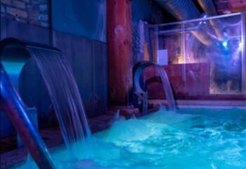 Adam Sauna Roma: Waterfalls fill a pool in a softly lit spa. A relaxing experience for gay men's travel in Rome, Italy.