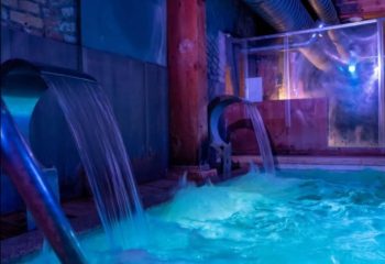 Adam Sauna Roma: Waterfalls fill a pool in a softly lit spa. A relaxing experience for gay men's travel in Rome, Italy.