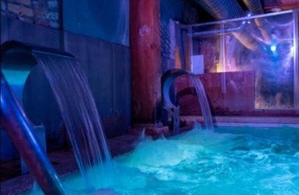 Adam Sauna Roma: Waterfalls fill a pool in a softly lit spa. A relaxing experience for gay men's travel in Rome, Italy.