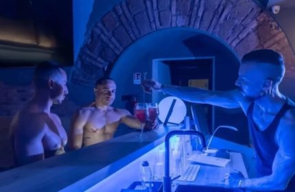 Adam Sauna Roma: Gay men at the bar. Two shirtless men are served drinks by a bartender in a gay sauna in Rome, Italy.