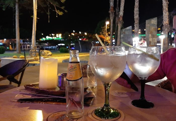 Night view at Adonis Bar, a gay bar in Gran Canaria. Drinks on a table with lights in the background, perfect for gay travel.