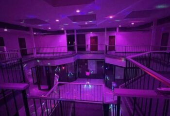 Interior of Adonis Health Club, a gay cruising spot in Las Vegas, featuring multi-level balconies and purple lighting. Nightlife travel.