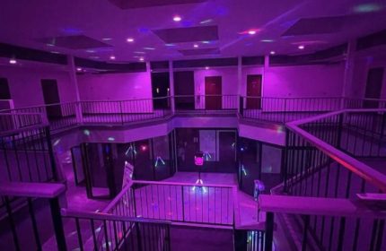 Interior of Adonis Health Club, a gay cruising spot in Las Vegas, featuring multi-level balconies and purple lighting. Nightlife travel.