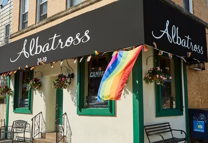 Albatross Bar in New York. The bar's exterior with rainbow flag, plants, and benches. A popular gay bar in Astoria, Queens, NYC.
