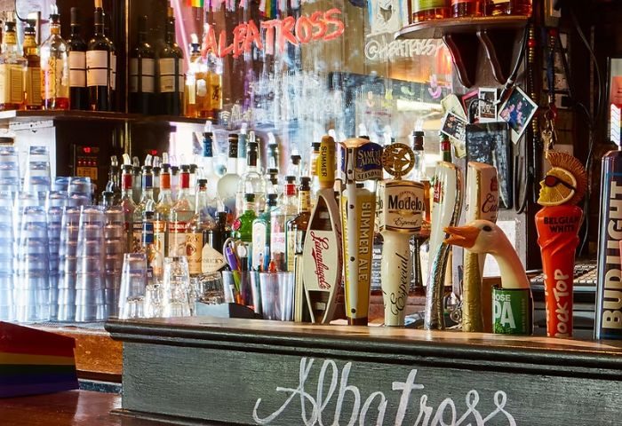 Albatross Bar in New York: A gay bar with a fully stocked bar, beer taps, and rainbow flag. A popular spot for gay men's travel in NYC.