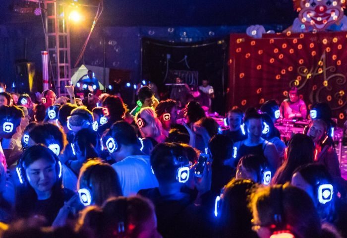 Silent disco at Albatross Bar in New York. People wearing glowing headphones dance in a crowded room at this popular gay bar.