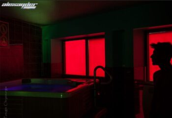 Alexander Sauna men's club: Interior shot of a hot tub with a silhouette of a man in front of a window with red light. Gay sauna travel.
