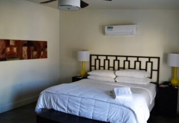 All-Worlds Resort gay rooms in Palm Springs: Clean room with bed, headboard, lamps, and art. Comfortable lodging for gay travelers.
