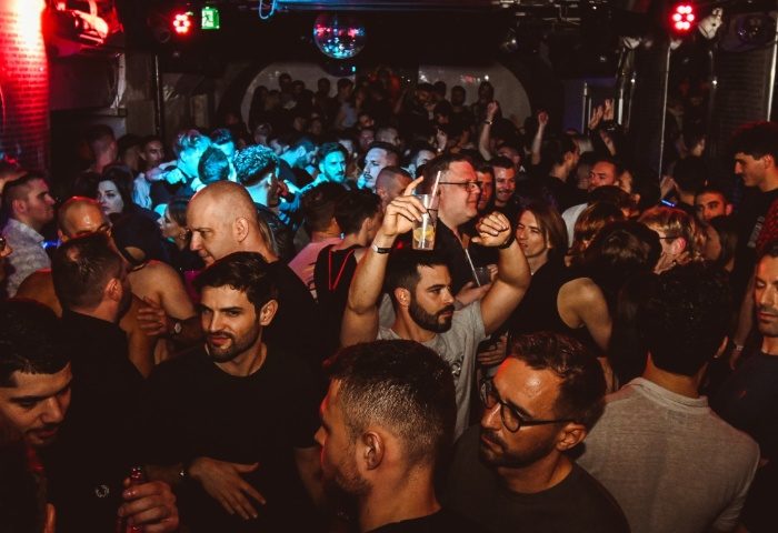 AlterEgo Club Budapest: A vibrant, crowded gay club scene. Men are dancing, drinking, and socializing under disco lights. Nightlife.