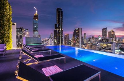 Amara Bangkok Silom gay hotel rooftop pool at dusk. Bangkok skyline view from the pool deck. Gay travel in Bangkok, Thailand.